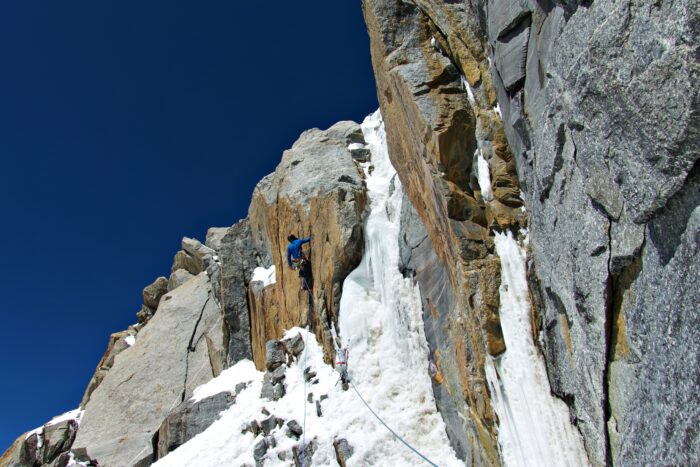 a cloimber on a rocky crack surrounded by ice sections.